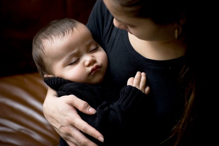 Baby sleeping in arms of her mother.