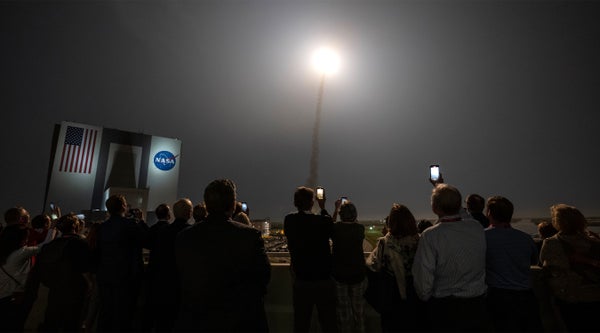 Guests holding up smart phones at night to watch the launch of NASAs Space Launch System rocket carrying the Orion spacecraft on the Artemis I flight test, from Launch Complex 39B.