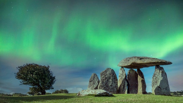 Standing stones in the style of Stonehenge, with Northern Lights glowing green in the background.