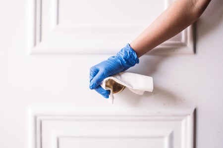 Gloved hand opening door with paper towel.