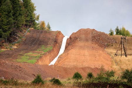 White pipeline being laid under red soil