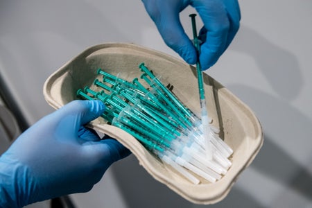 Gloved hands hold a container of Covid-19 vaccines.