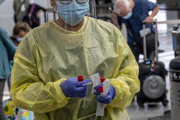 A medical worker carries nasal swabs at a COVID testing site in the San Francisco Airport.