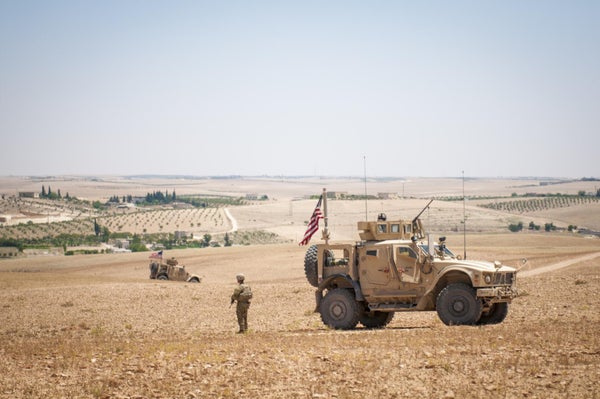 US soldiers patrolling dry field in Syria.