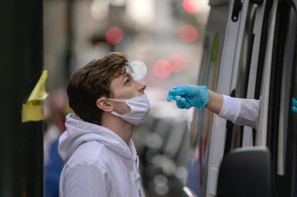 A person in a medical vehicle sticks an arm out a window to perform a Covid swab test.