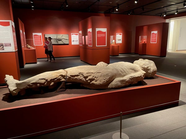 10-foot-tall gypsum stone sculpture displayed on orange case in museum