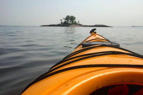 Nose of kayak on the water, headed toward small island.