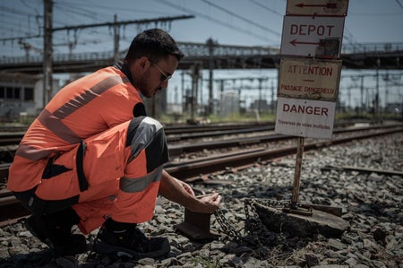 A SNCF employee checks the temperature of the railway tracks outside the railway station in Bordeaux, southwestern France, on June 15, 2022 as a heatwave hits France.