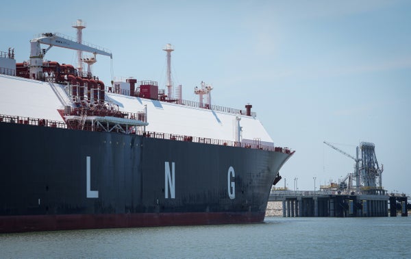 Natural gas transport ship with LNG letters on side sits docked.