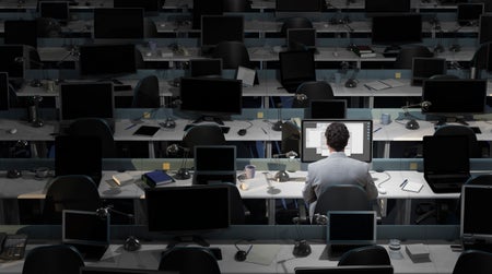 An office worker sits working in an empty office