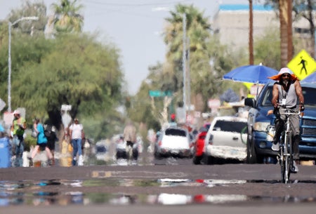 A man on a bicycle on a street shimmering with heat