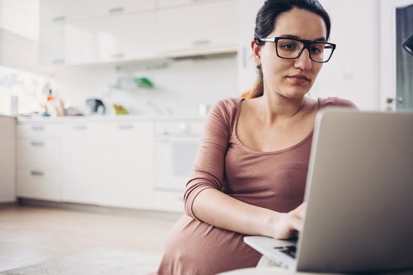 Pregnant woman with a laptop in the kitchen.