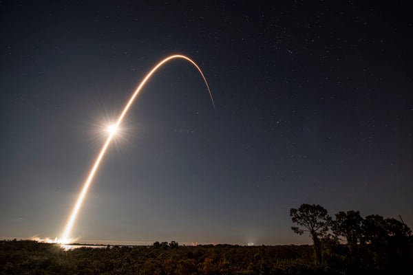 Time-lapse image of rocket taking off against darkened sky.