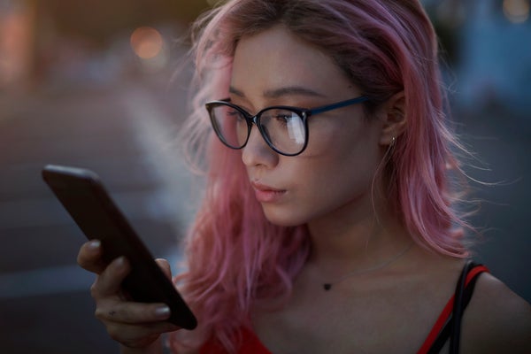 Young woman with black glasses and strawberry hair holding a smart phone