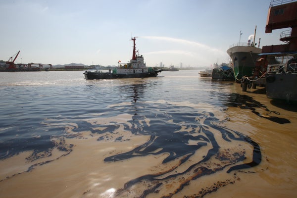 Oil slick on the water with ship in background