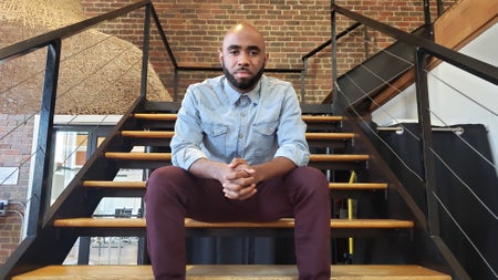 Nehemiah Mabry, an engineer and entrepreneur, sits on a staircase looking at the camera