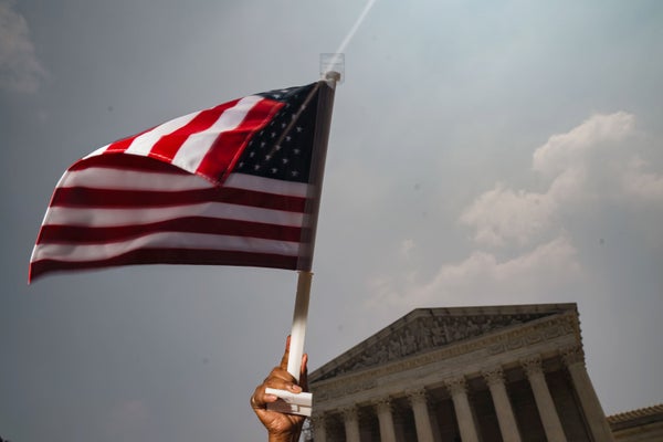 Hand holding flag outside U.S. Supreme Court building