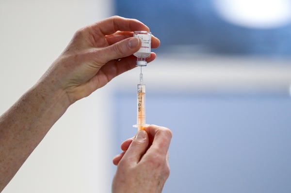 A healthcare worker fills a syringe with a dose of AstraZeneca's COVID-19 vaccine.
