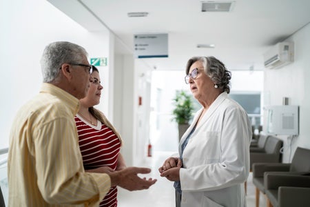 A female doctor speaks with two patients.