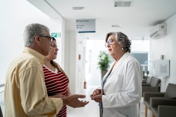 A female doctor speaks with two patients.