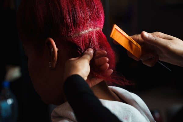 Hair stylist brushing a Black clients hair in a beauty salon