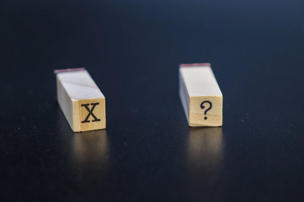 2 wooden blocks with "X" and "?" letters on blue background
