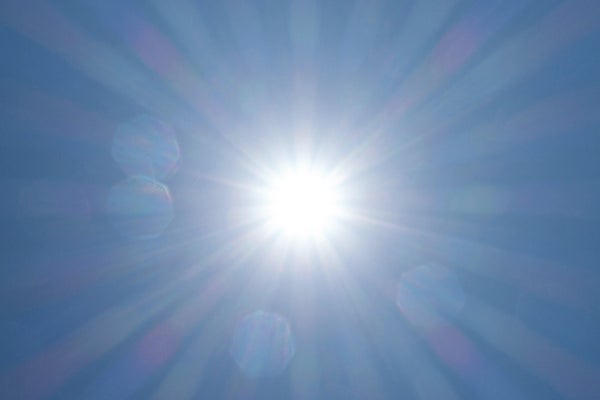 Image of the sun looking directly at it in a sunny day with a blue sky