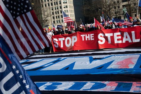 People hold a giant red banner during a march.