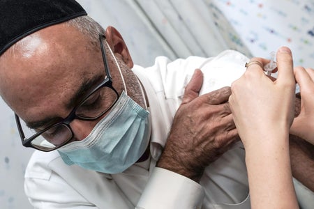 A masked man recieves a vaccination.