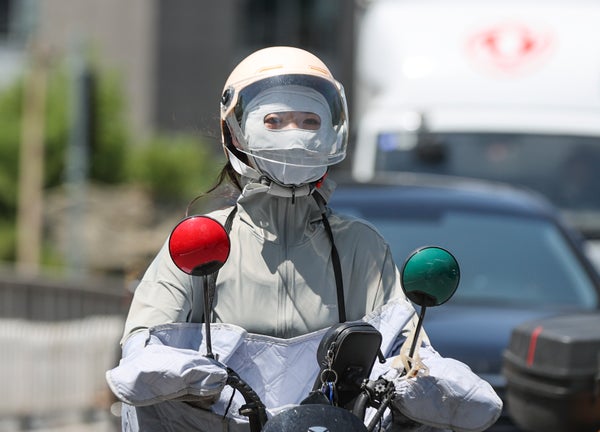 Person on electron motorbike draped in white protective fabric and clothing.