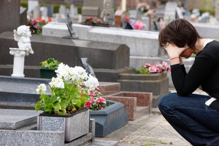 Woman sitting by a grave.