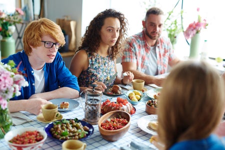 Young people sitting by Thanksgiving table, dining and talking