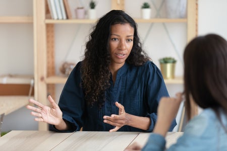 lose up confident businesswoman sitting at table speaking to someone.