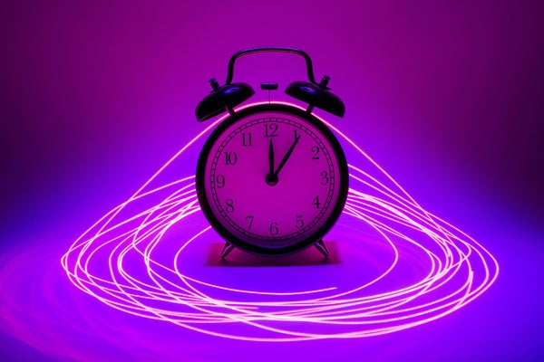 creative artist's concept showing a traditional alarm clock encircled by a laser light effect
