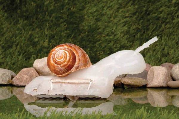 A large robot snail on the surface of some water with rocks in the background.