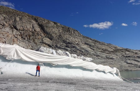 Person standing in front of tarp-covered glacier