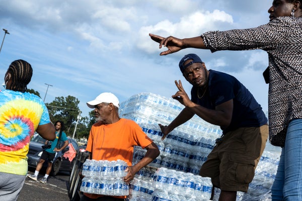 4 people handing out cases of bottled water.
