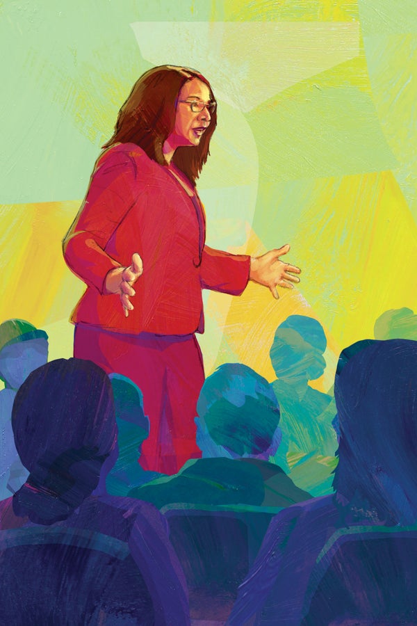 Woman wearing red suit speaking to an audience.
