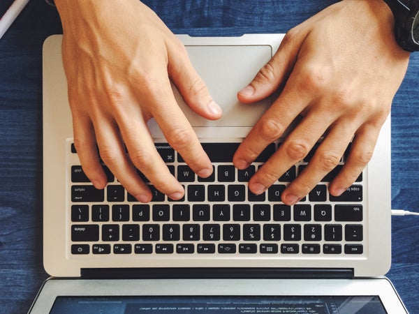 Close-Up Of Hand On Laptop Keyboard