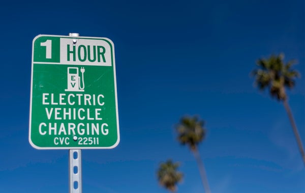 Electric vehicle charging station sign, Los Angeles, CA. with palm tree background.