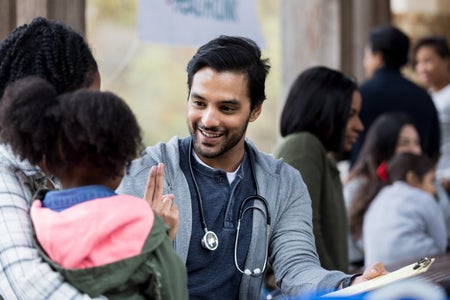 Doctor surrounded by patients checks a little girl's vision.