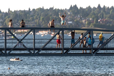 People sitting and a man jumping from the South Lake Union Park Bridge