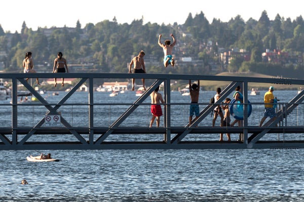 People sitting and a man jumping from the South Lake Union Park Bridge