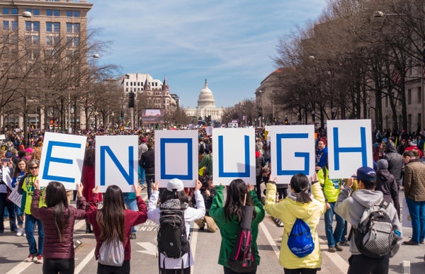 Students with backpack holds signs that spell "ENOUGH" at gun violence protest