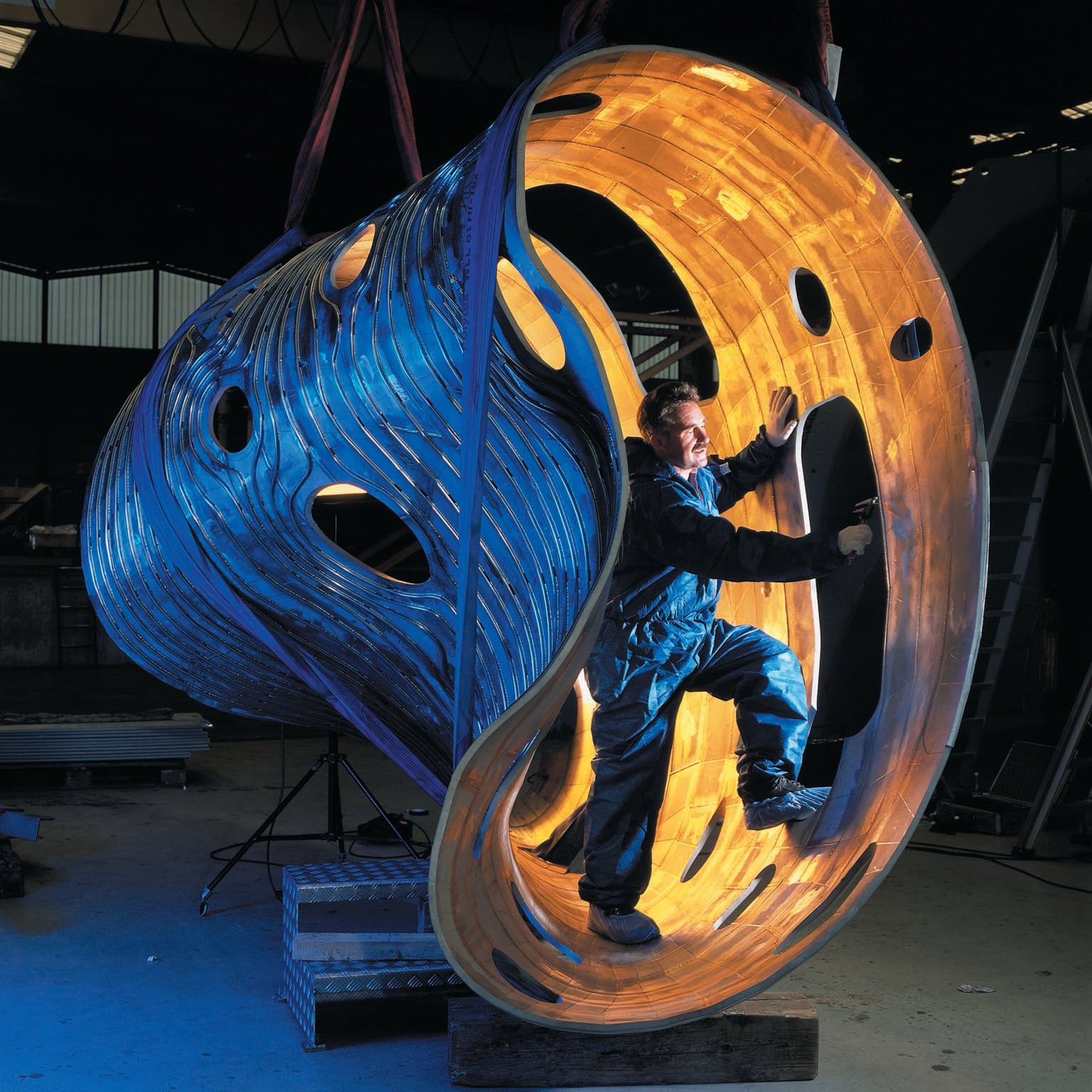 Man standing inside of a piece of metallic industrial part.