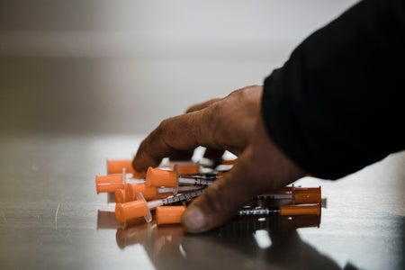Close-up of hand picking up syringes