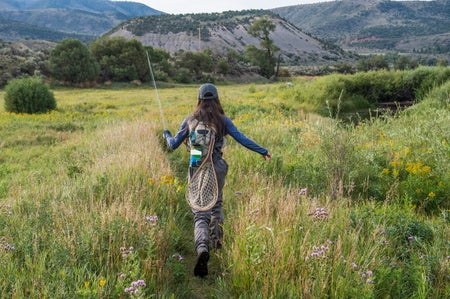 Female angler walking through meadow