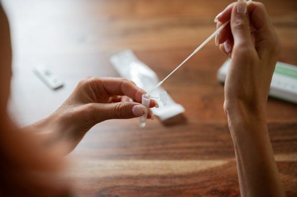 A hand holding a cotton swab for a home COVID test.