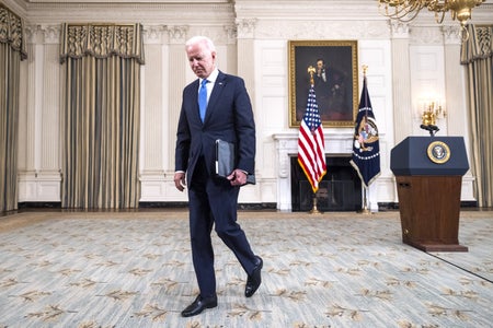 President Biden walking inside White House office.