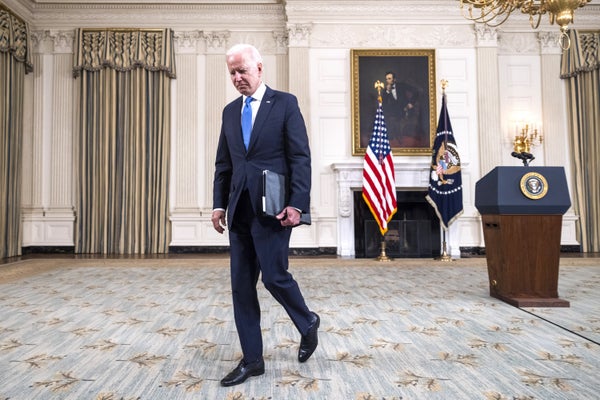 President Biden walking inside White House office.